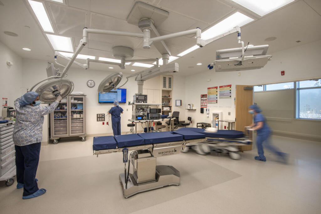 Three surgical technicians prepare an operating room for a patient