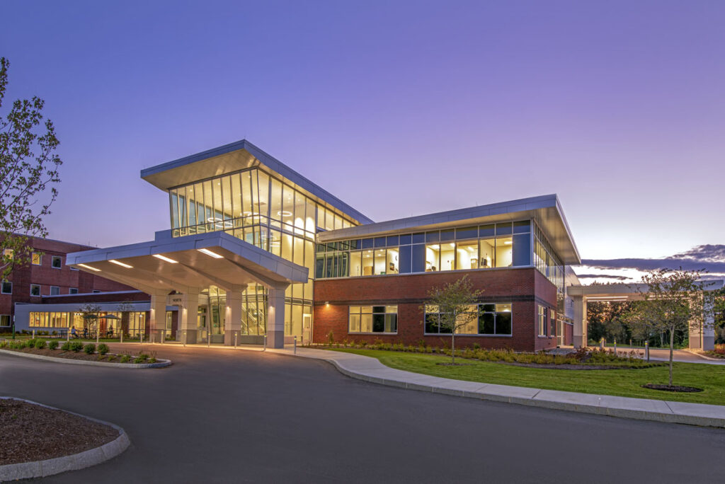 The exterior view of the front entrance of a medical office building constructed of brick at dusk on a summer evening.