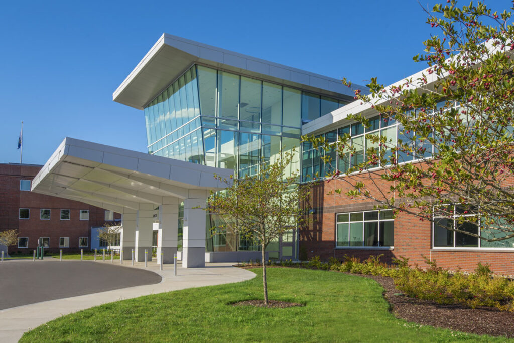 The exterior view of the front entrance of a medical office building constructed of brick at midday on a clear-sky summer day.