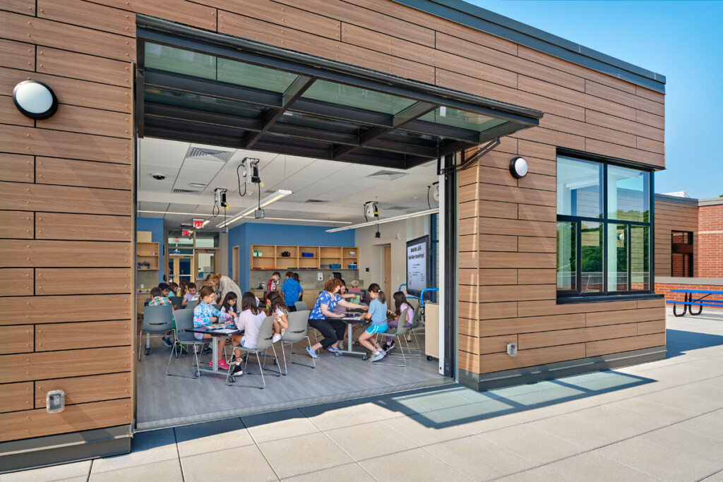 Classroom of students with a garage door leading out to a patio.